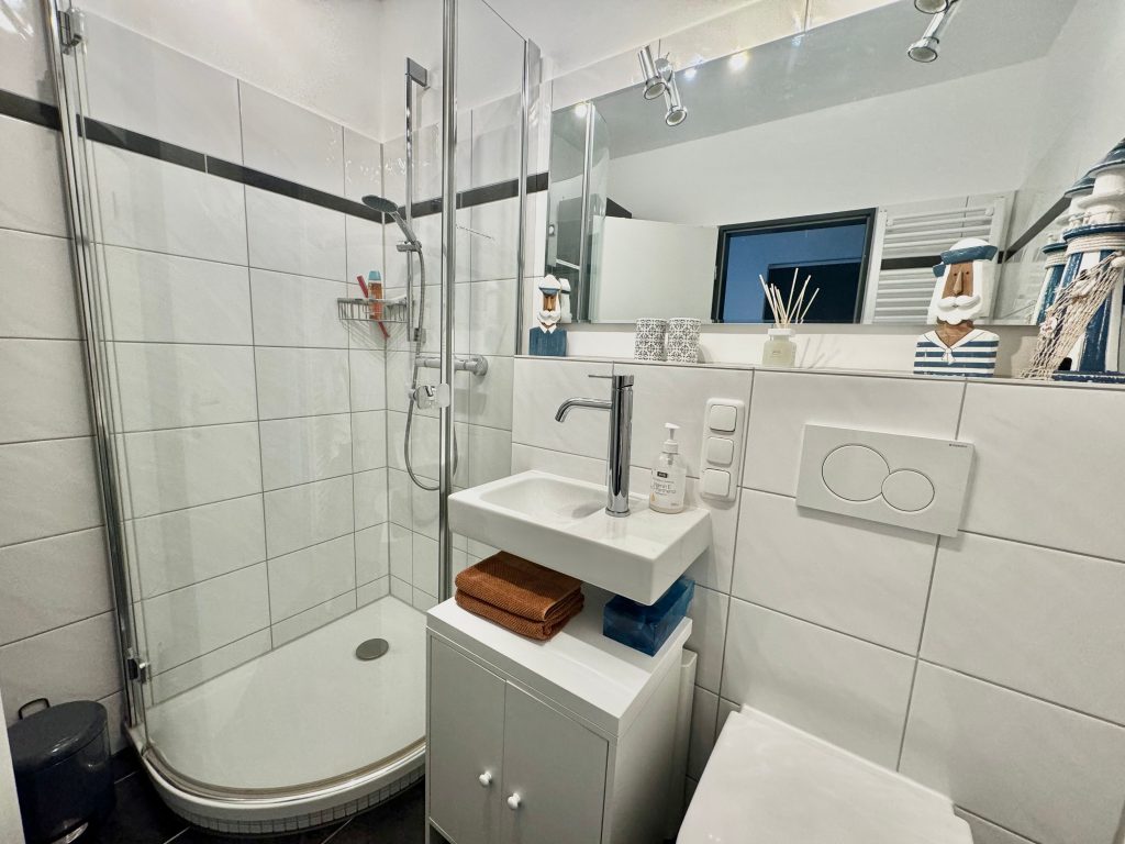 Badezimmer mit Dusche und Spiegel in Ferienwohnung an der Ostsee